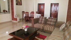 A living room with a sofa, a coffee table, and a dining area with chairs and a table. - Family Nest Kivu Beach (Nyayumba)