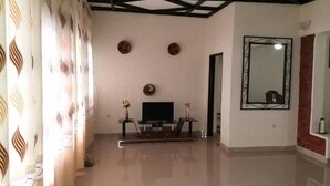 A spacious living room with a flat-screen TV, a coffee table, and decorative items on the wall. - Family Nest Kivu Beach (Nyayumba)