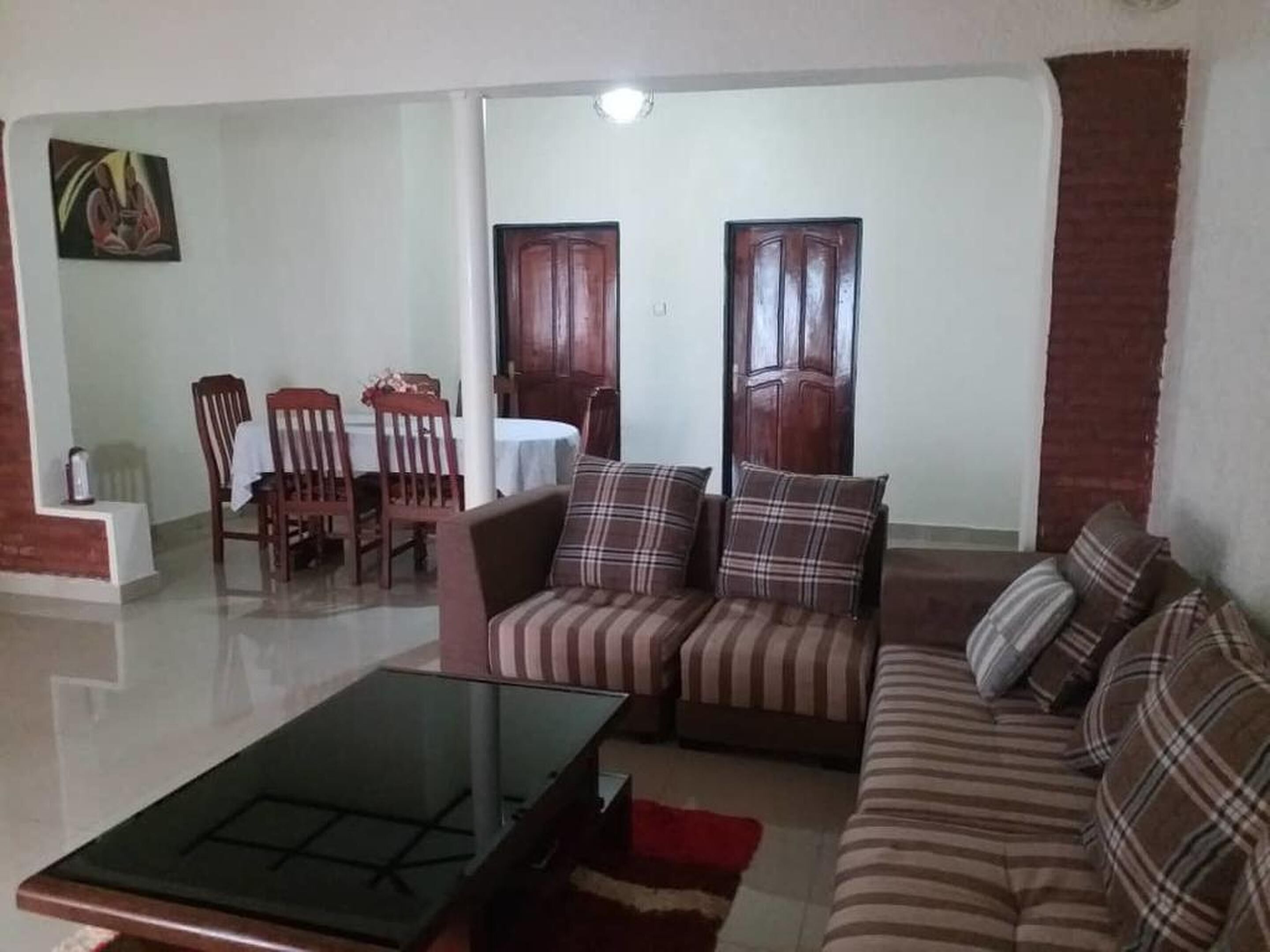 Una sala de estar con un conjunto de sofá, una mesa de centro de vidrio y un comedor con sillas y una mesa.