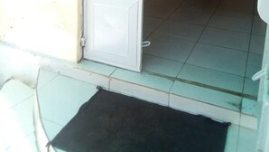 A hallway with a white door, tiled floor, and a black mat at the entrance. - Paulice Guest House (Kisumu)