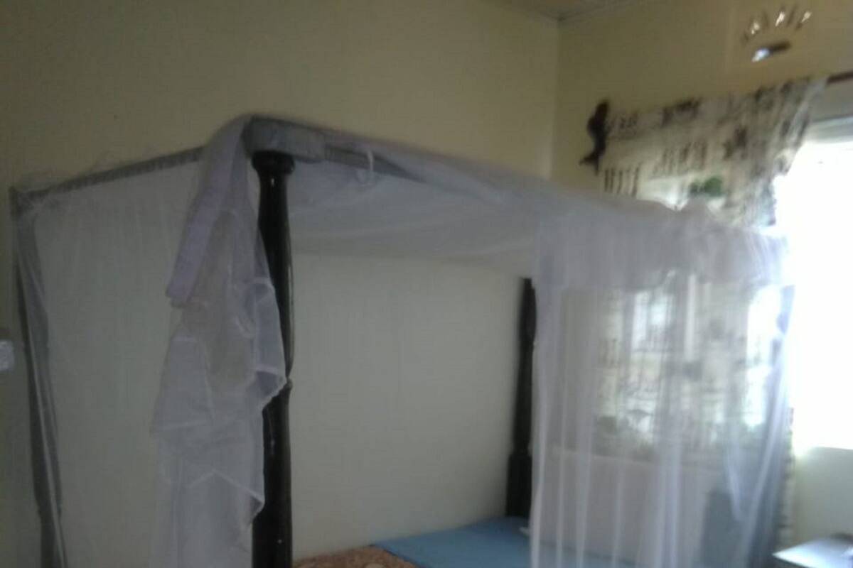 A four-poster bed with a mosquito net, a patterned bedspread, and a small table with a chair.