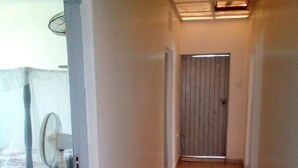 A narrow hallway with tiled flooring, a ceiling fan, and a door at the end. - Paulice Guest House (Kisumu)