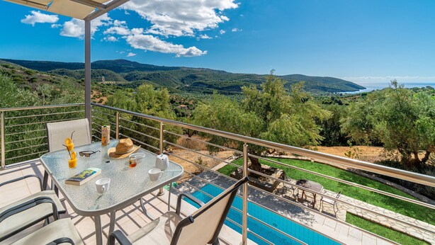 A balcony with a table set for two, overlooking a pool and a scenic landscape. - Schiza Houses (Pylos-Nestoras)