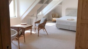 A bedroom with a white bed, a white sofa, and a wicker chair. There is a window providing natural light. - Guest house beautiful historic square farm 🎯 in Ranst (Broechem Antwerp)