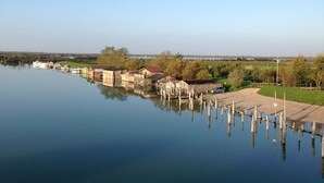 Un lago tranquilo con un muelle que se adentra en el agua, rodeado de edificios y follaje.