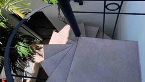 A spiral staircase with a metal railing, leading to an upper floor.