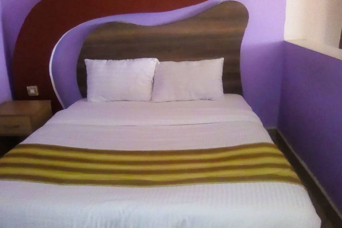 Un llit amb un estriat, un reposacapses i dos almoines.