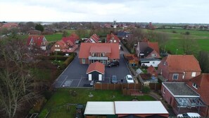 A residential area with houses, a central building with a parking lot, and a windmill in the background.