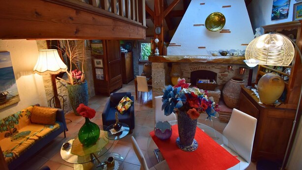 Een gezellige woonkamer met een open haard, houten balken en een eethoek.