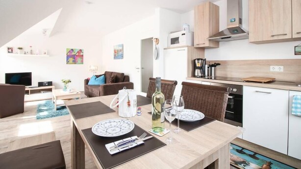 Une cuisine moderne avec des meubles en bois, un four à micro-ondes et un coin repas avec une table dressée pour deux personnes.