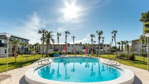 A swimming pool surrounded by palm trees and modern buildings. - Waterview penthouse condo on inter coastal waterway with pool (Fort Walton Beach)