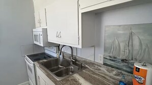 A compact kitchen with white cabinets, a microwave, a sink, and a dishwasher. - Waterview penthouse condo on inter coastal waterway with pool (Fort Walton Beach)