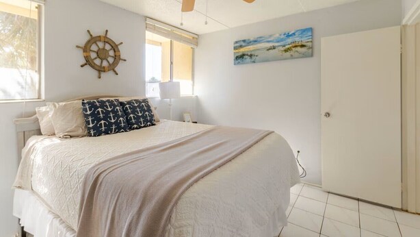 A bedroom with a bed, a ceiling fan, a ship's wheel decoration, a painting, and a door. - Waterview penthouse condo on inter coastal waterway with pool (Fort Walton Beach)