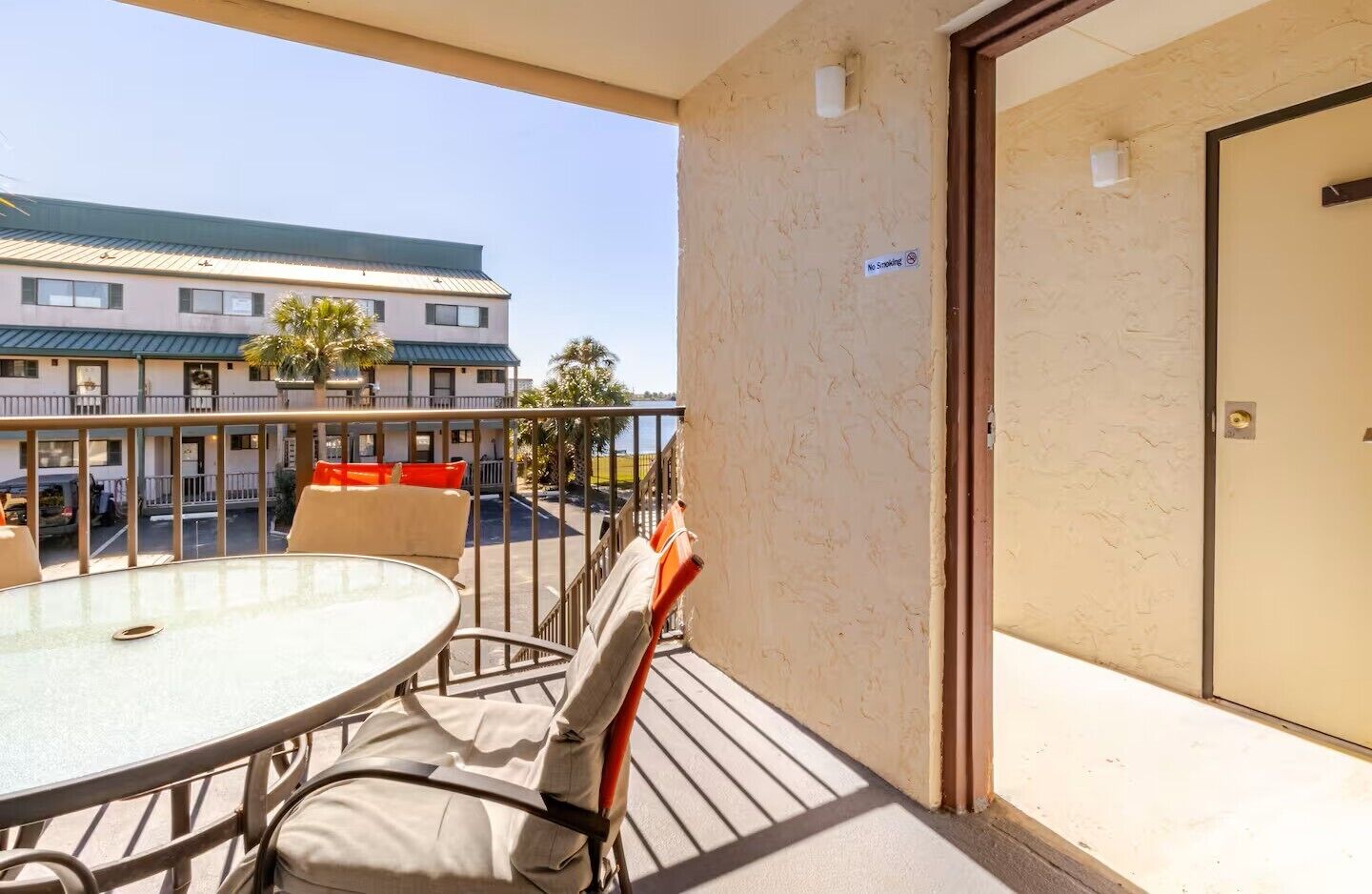 Ein Balkon mit Tisch und Stühlen, einer Tür und Blick auf ein Gebäude mit einer grünen Dachbegrünung.
