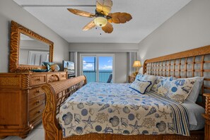 Ein Schlafzimmer mit Bett, Kommode, Spiegel, Deckenventilator und Meerblick.