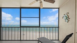 Un balcón con vista a la playa, un ventilador de techo y una banca.