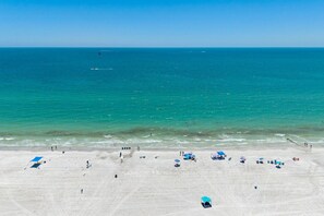 A beach with clear turquoise water, a sandy shore, and several umbrellas.
