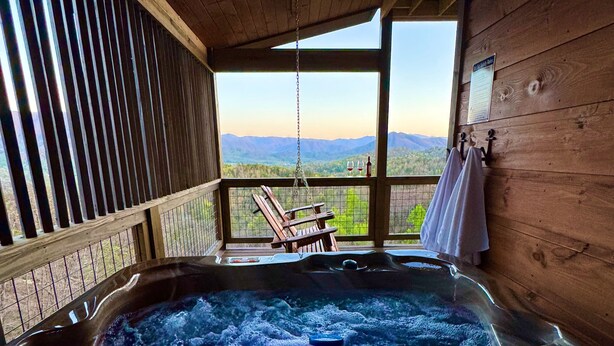 A hot tub with a view of mountains, wooden walls, and a hanging chair. - MORE THAN A GORGEOUS CABIN, IT'S AN EXPERIENCE!!!!  CLOSE TO ATTRACTIONS & GSM (Sevierville)