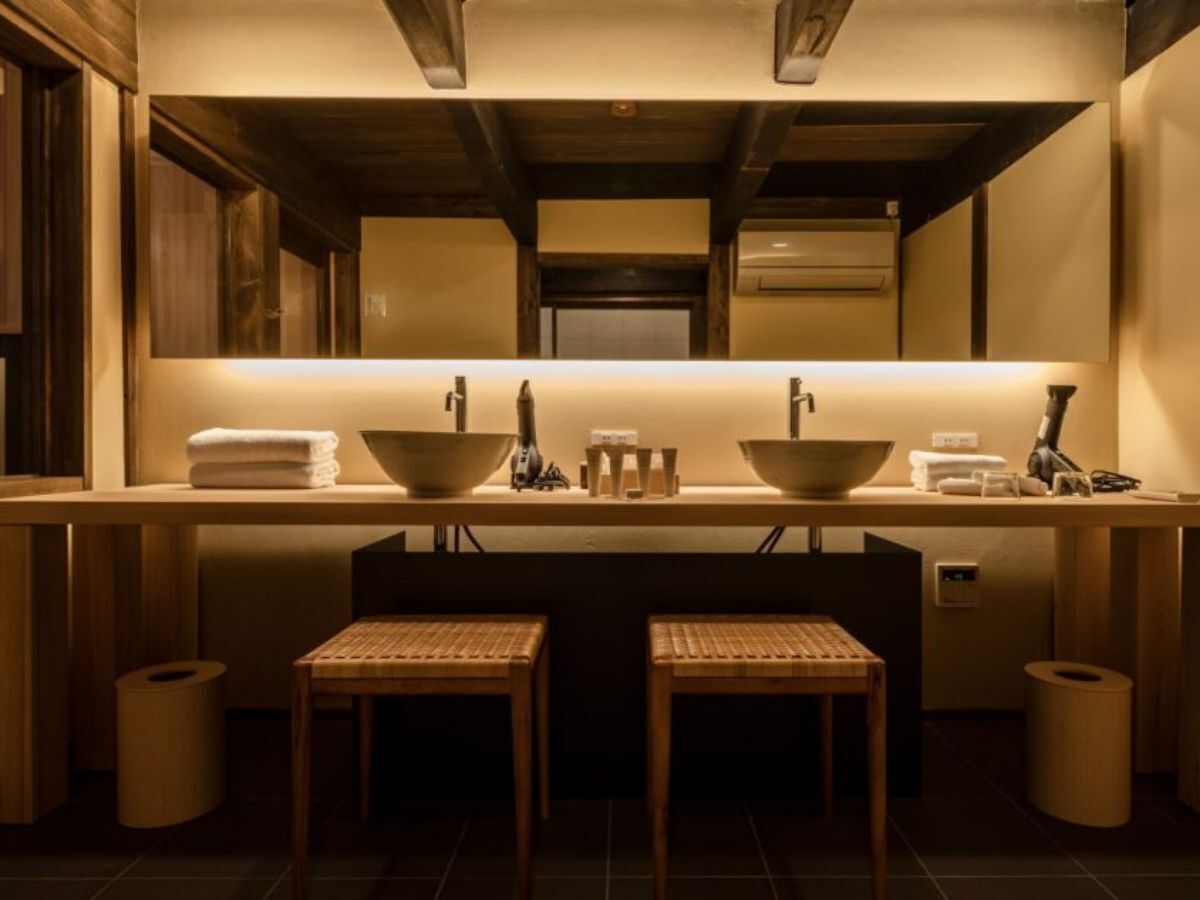 A modern bathroom with two sinks, a mirror, and wooden stools.