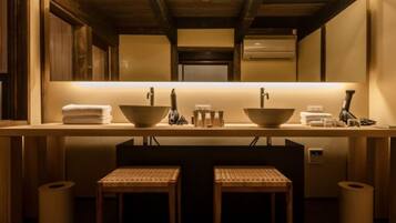 A modern bathroom with two sinks, a mirror, and wooden stools.