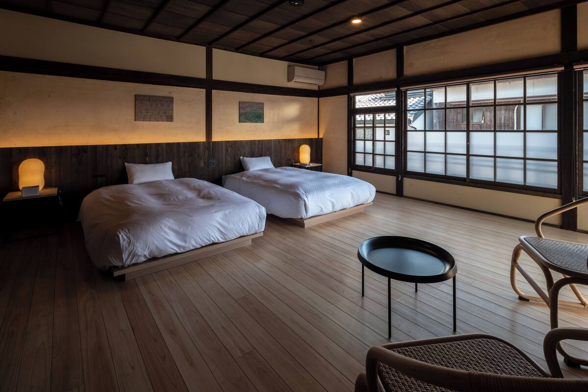 Una habitación de hotel con dos camas, una mesita redonda pequeña y una silla.