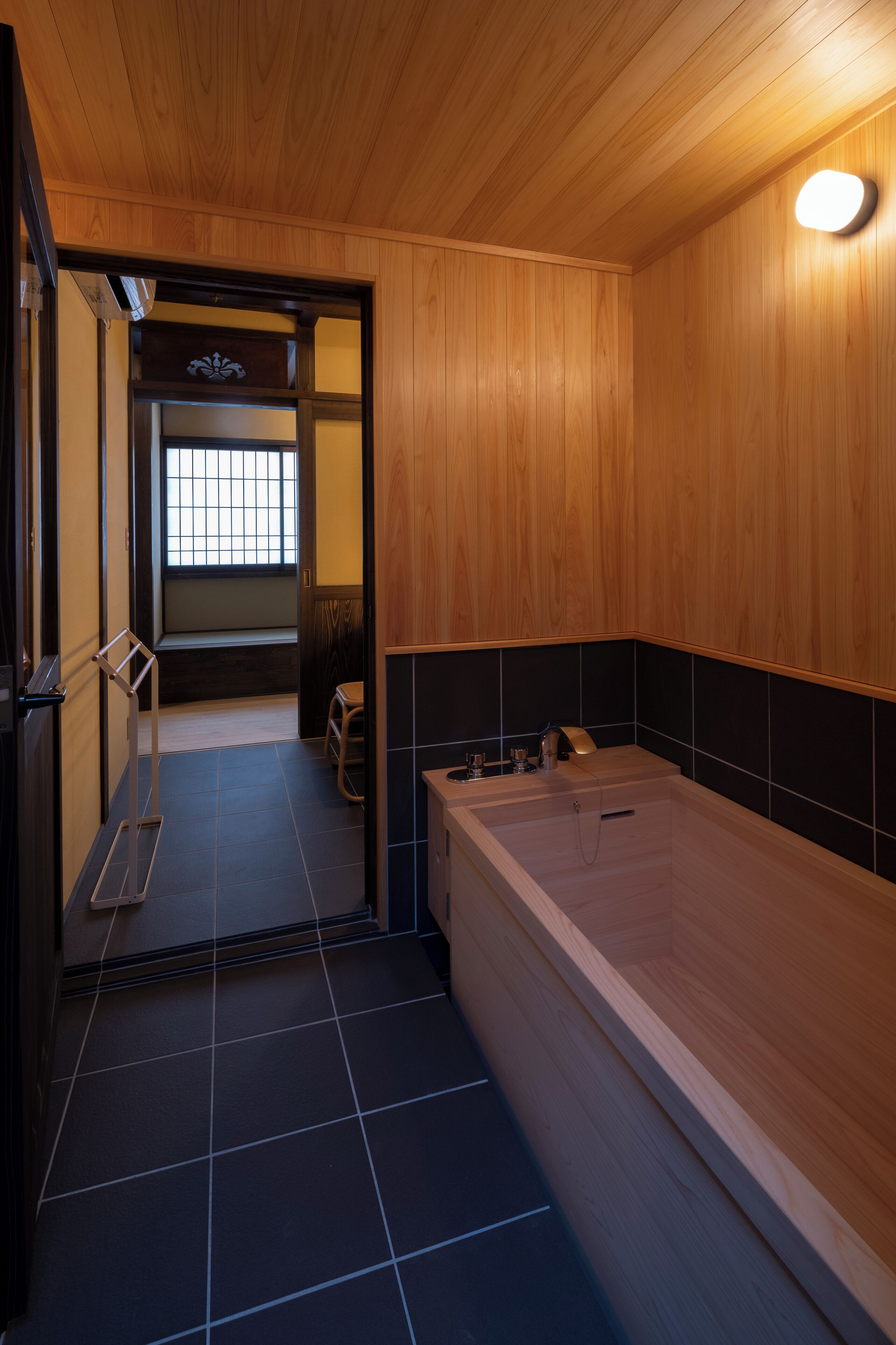 A wooden interior with a bathtub, tiled floor, and a bench.