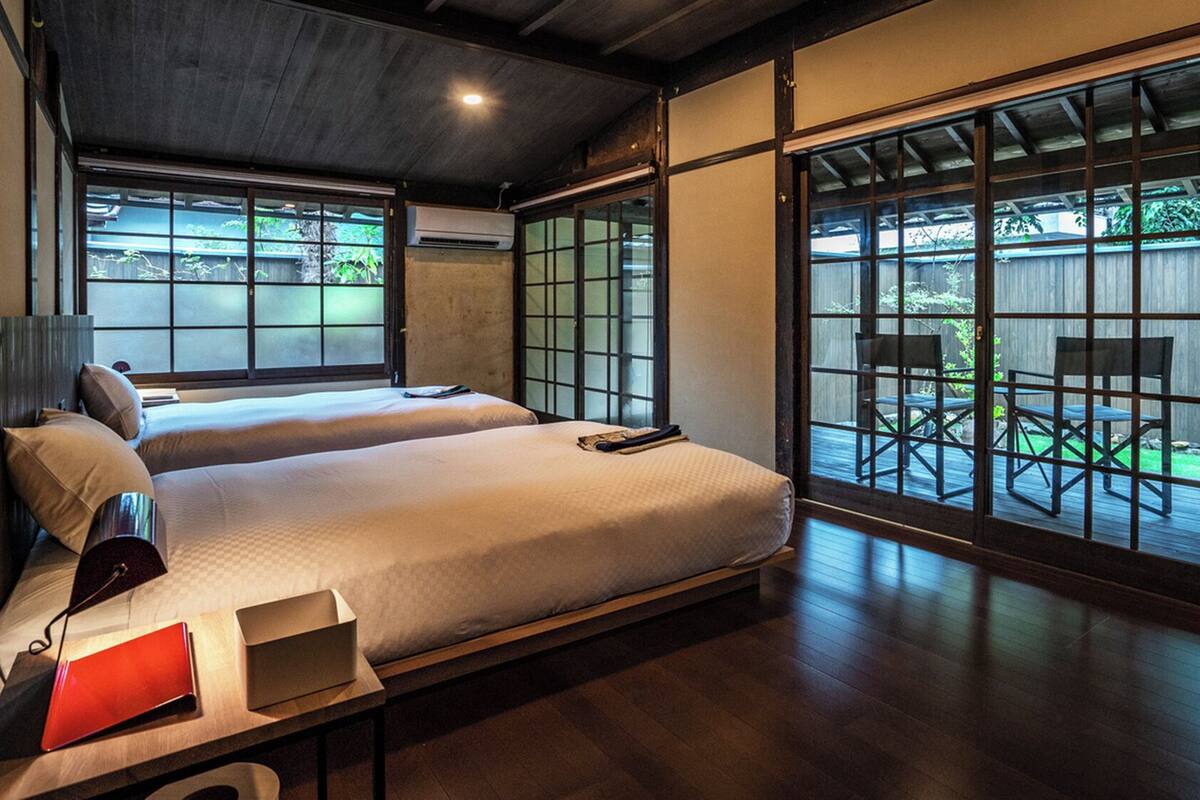 Una habitación de hotel con una cama grande, un escritorio y vistas a una terraza exterior por una puerta corrediza.