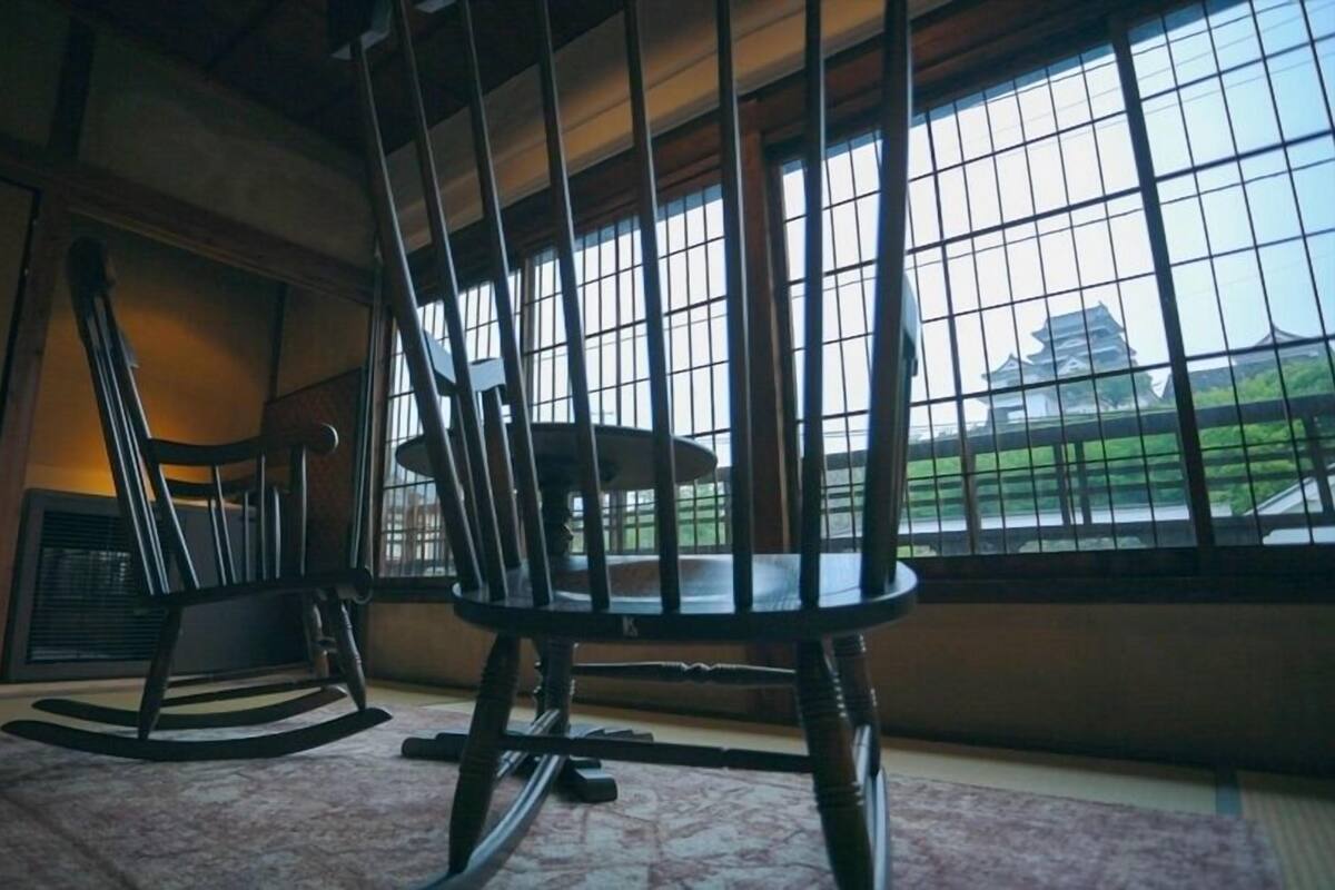 Una habitación japonesa tradicional con suelo de tatami, una puerta corredera y vistas a una pagoda a través de amplios ventanales.