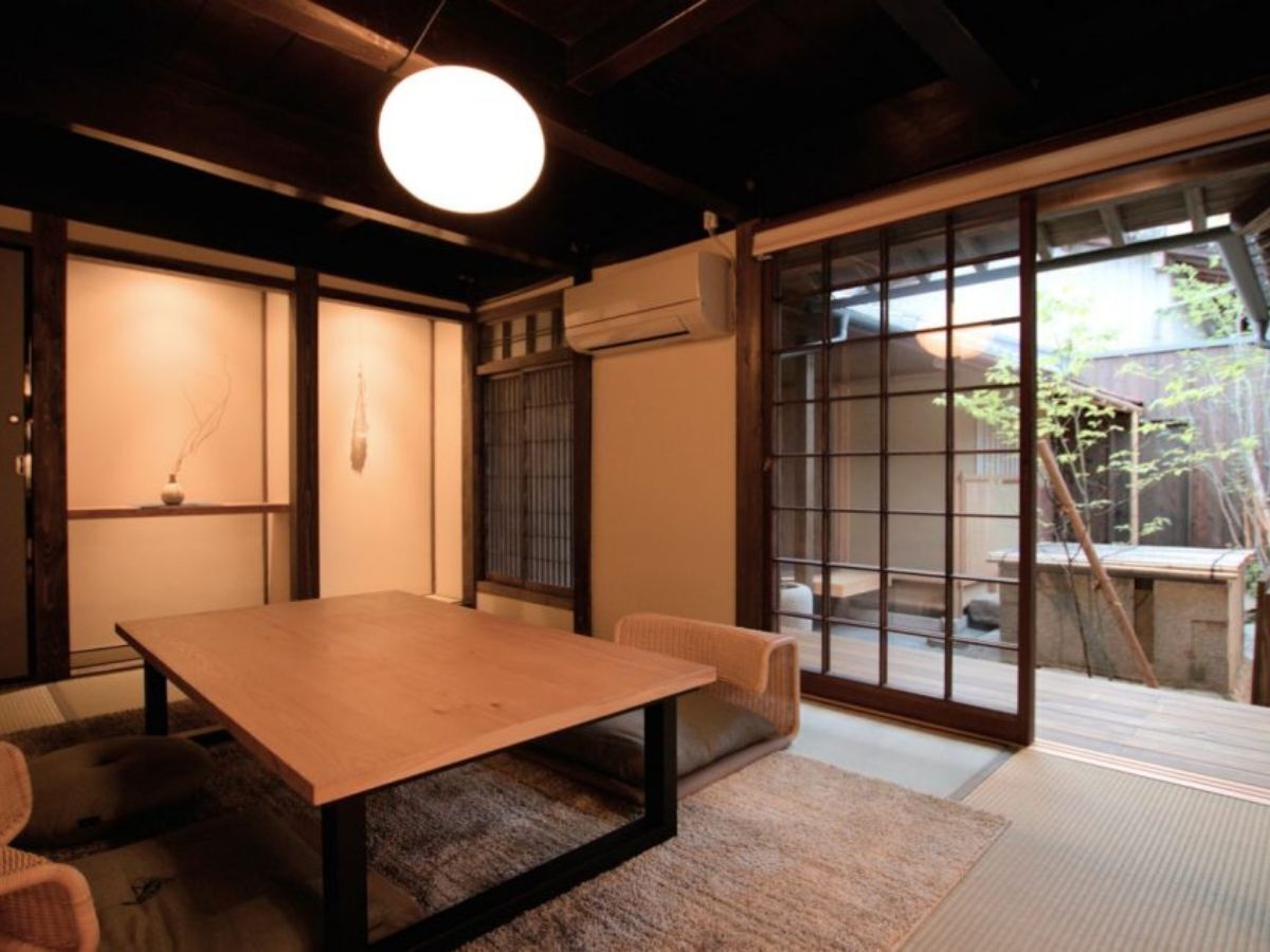 Une pièce de style japonais traditionnel, avec un sol recouvert de tatamis, une table basse, des portes coulissantes et une vue sur l’extérieur.