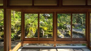 Una habitación tradicional japonesa con suelo de tatami y vistas a un jardín a través de una puerta corredera de madera.
