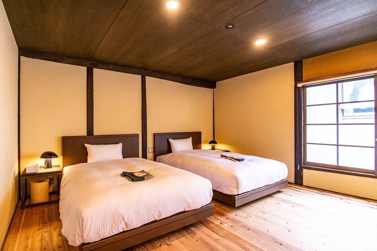 Habitación de hotel con dos camas, suelo de madera y un ventanal grande.