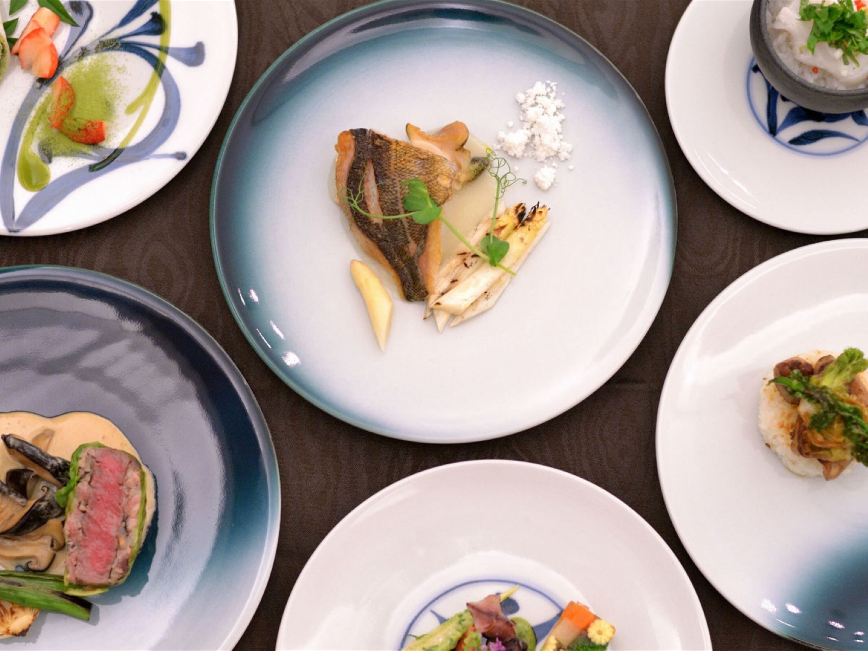 Une table à manger sur laquelle se trouvent de nombreuses assiettes remplies de différents plats.