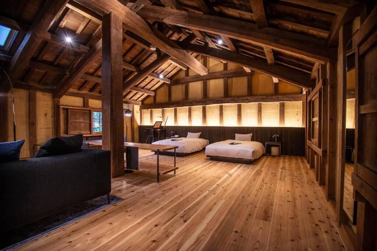 Una habitación rústica de madera con techo alto, un sofá, dos camas y un escritorio.