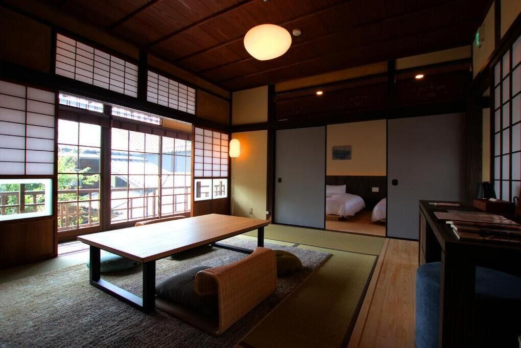 Una habitación japonesa tradicional con suelo de tatami, una mesa baja y puertas correderas.