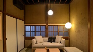 Una habitación japonesa tradicional con suelo de tatami, una mesa de madera baja, un sofá con cojines y una puerta corredera.