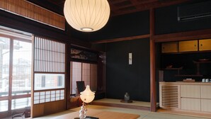 Una habitación tradicional japonesa con suelo de tatami, una mesa de madera, un farol de papel colgante y puertas correderas shoji.