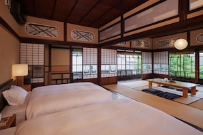 Una habitación tradicional japonesa con suelo de tatami, una mesa de madera baja y una cama con ropa de cama blanca.