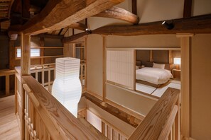 Une pièce de style japonais traditionnel, avec un sol recouvert de tatamis, un lit bas en bois et une vue sur la pièce située en dessous.