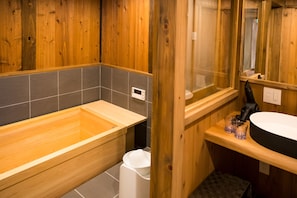 Un baño de madera con bañera, lavamanos y espejo.