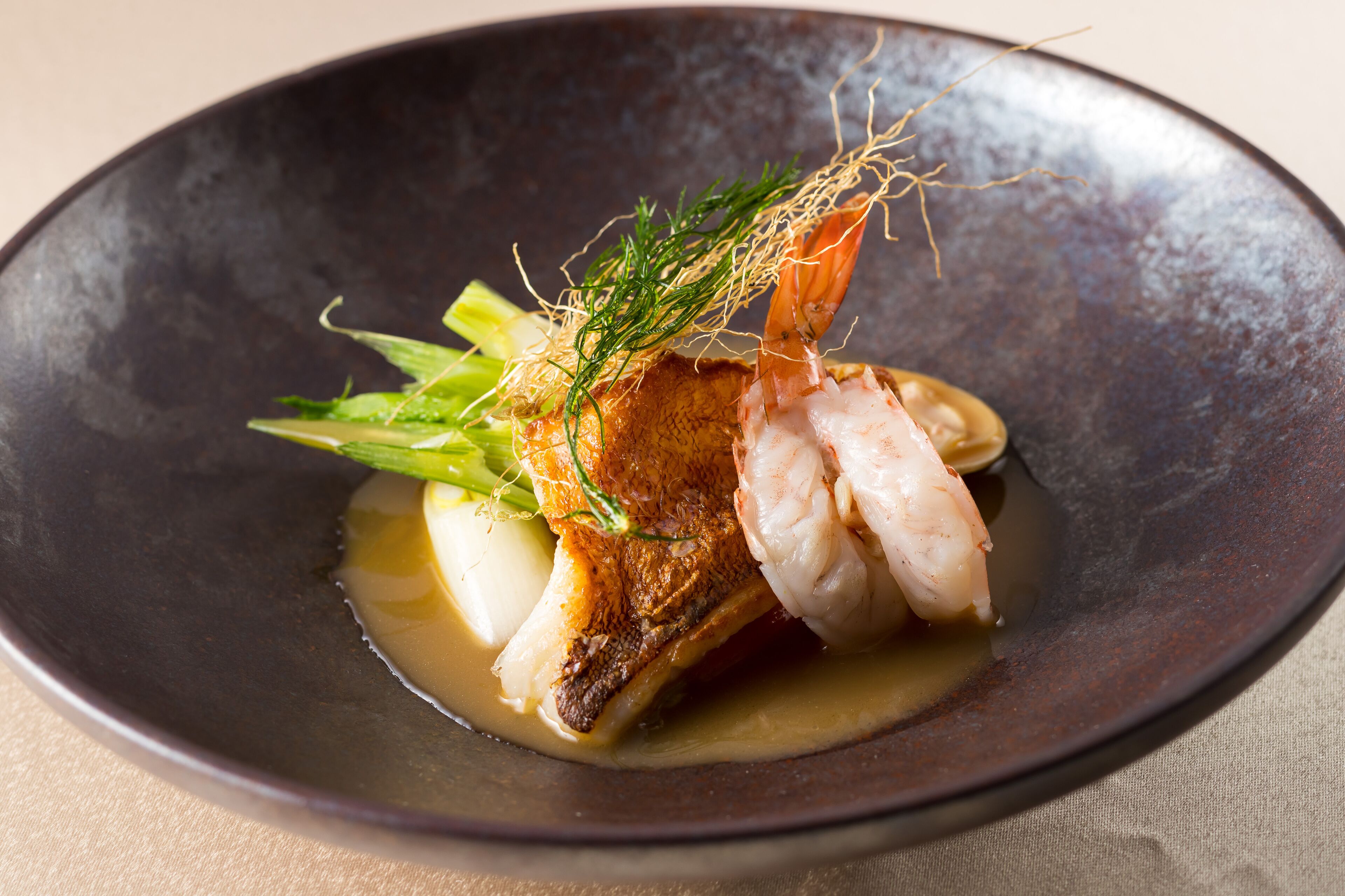 Un plato de pescado y verduras en un bol oscuro.