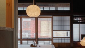 Una habitación japonesa tradicional con suelo de tatami, una mesa de madera baja y puertas correderas shoji.