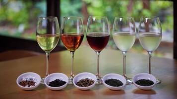 Seis copas de vino con líquidos de colores distintos y cuatro recipientes pequeños con diversas especias o hierbas.