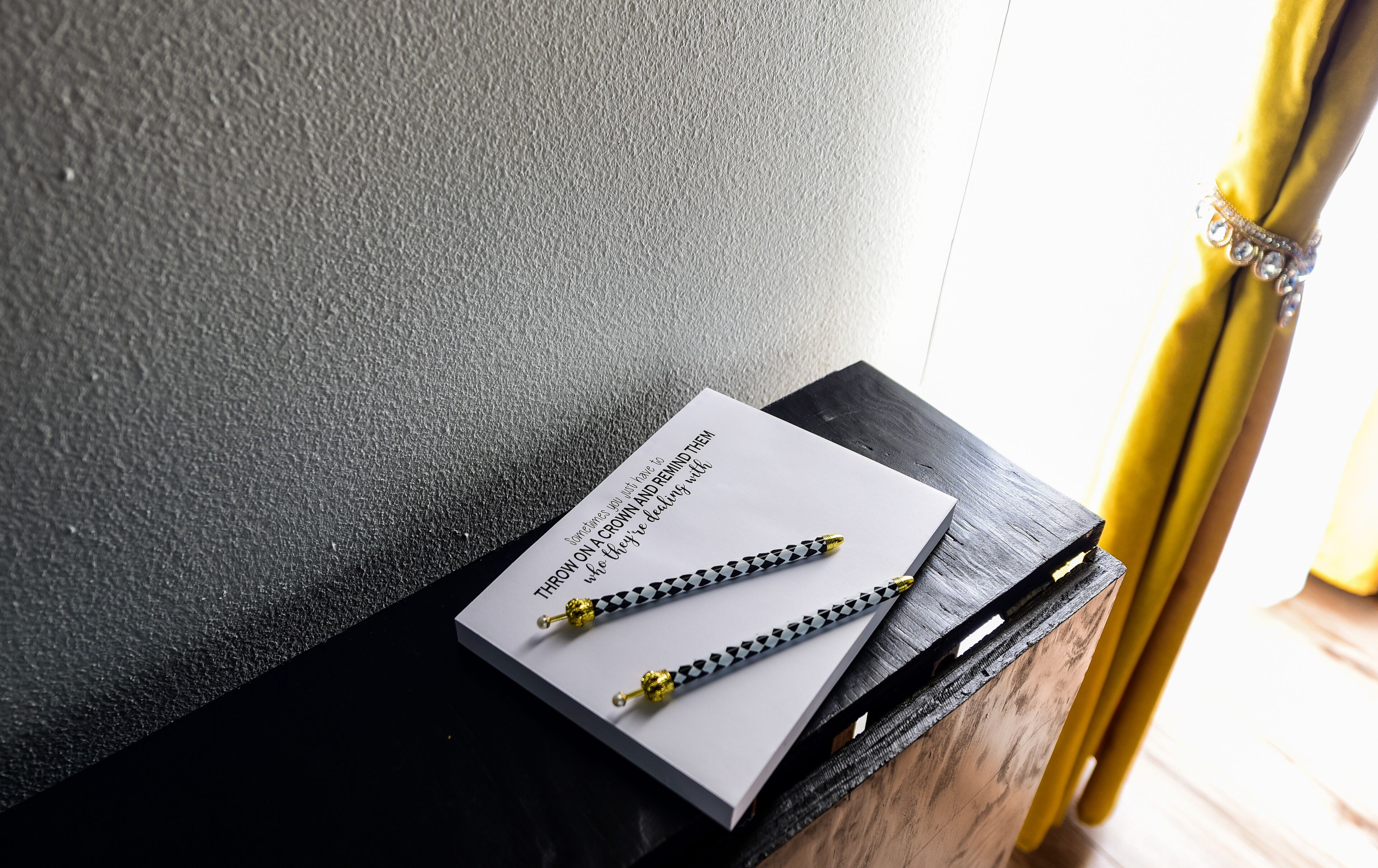 A black wooden table with a white card and two pens on it.