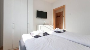 A bedroom with two beds, a wardrobe, a desk, and a television. - Kerstins Mühlenplatz (Krummhoern)
