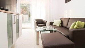 A modern living room with a glass coffee table, a brown leather sofa, and a brown leather armchair. - Kerstins Mühlenplatz (Krummhoern)