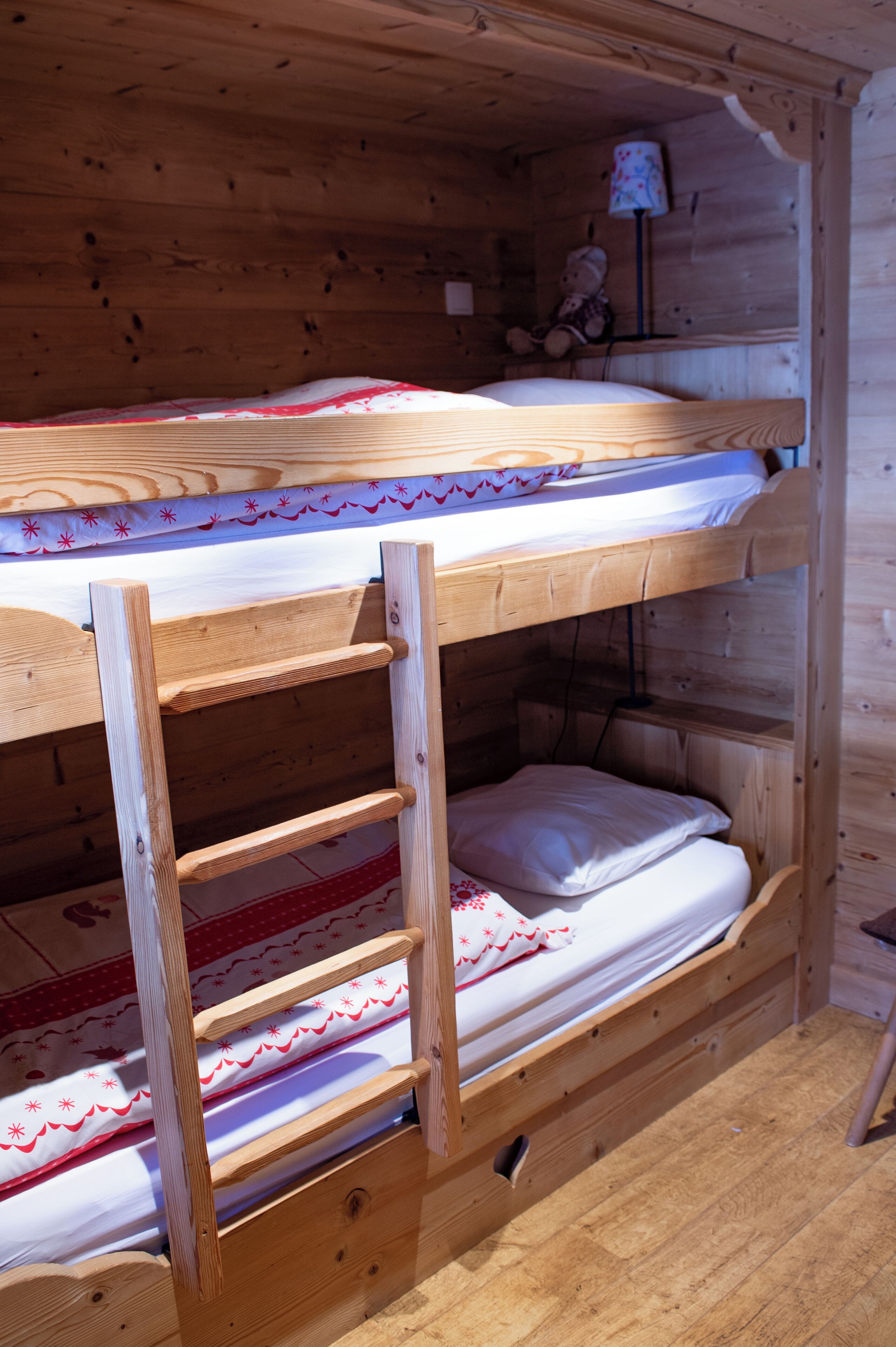 A bunk bed with a wooden ladder and a small shelf.