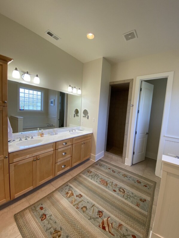 A bathroom with a double sink vanity, a large mirror, and a patterned rug.