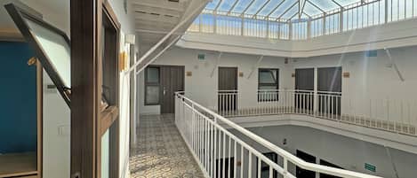 A multi-level interior with a glass ceiling, white railings, and patterned flooring.