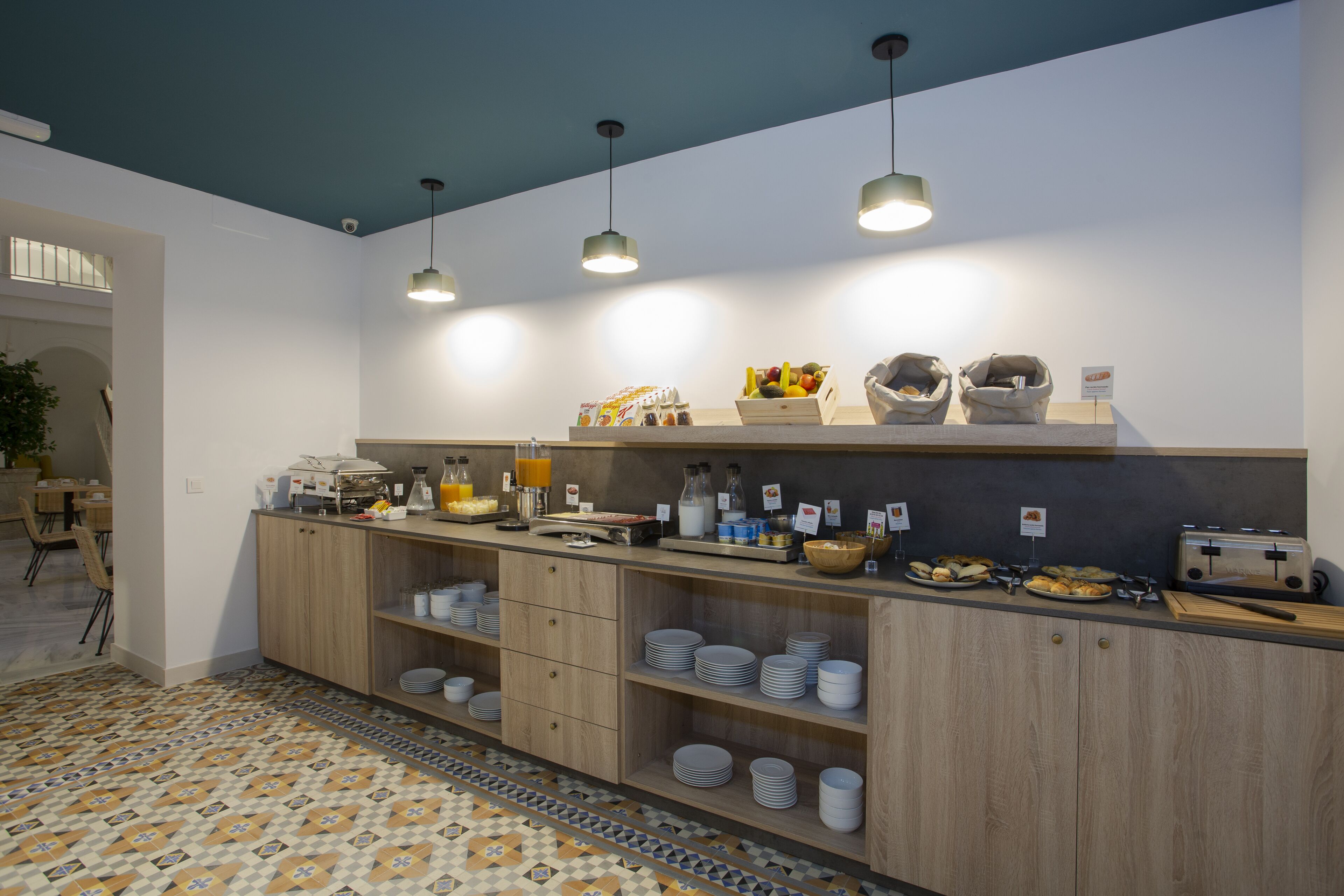Una cocina moderna con armarios de madera, una encimera con distintos alimentos y lámparas colgantes.