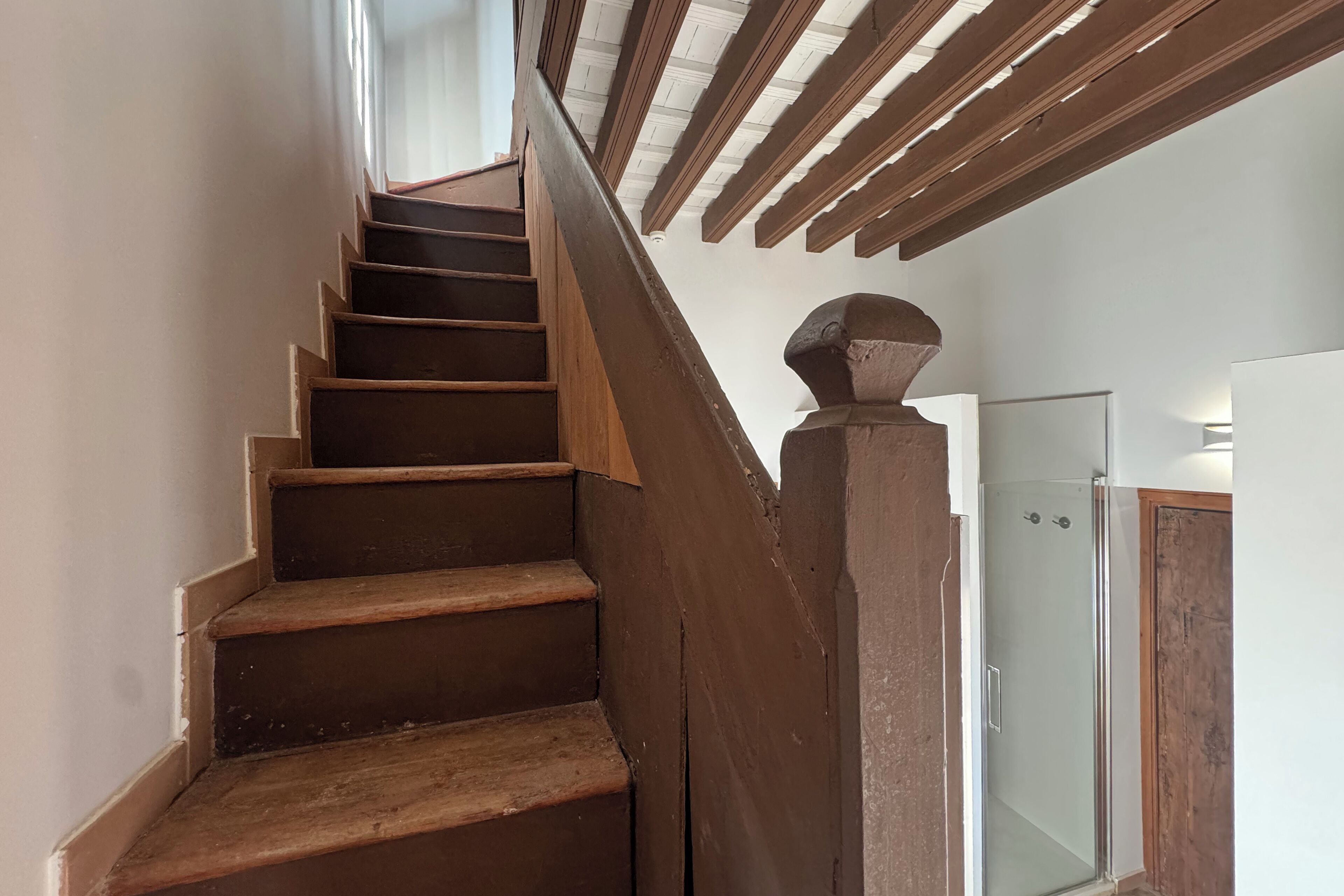 Una escalera de madera con un vidrio en la parte superior que da a una habitación.
